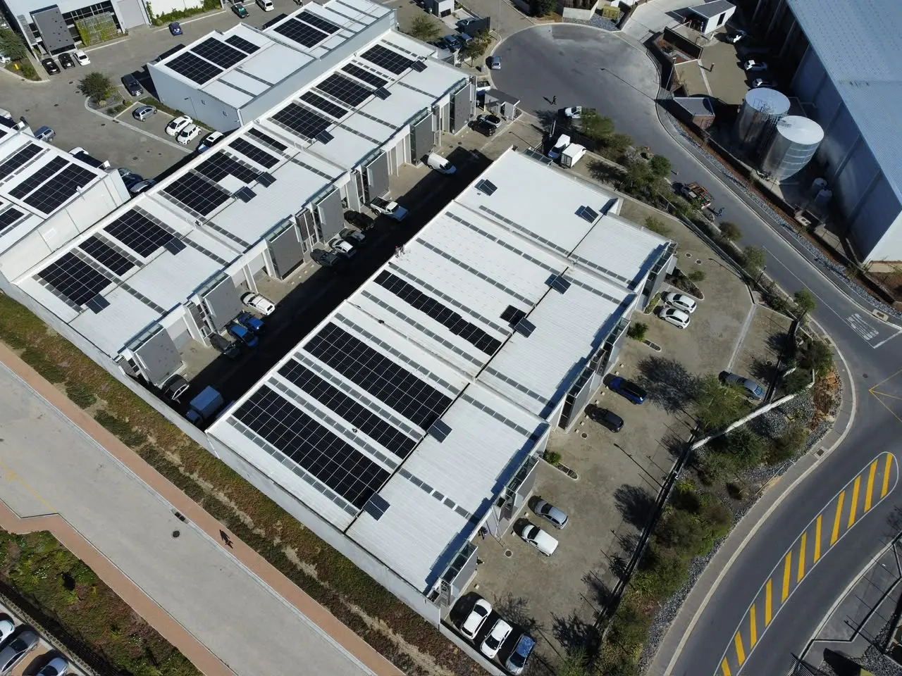 Aerial view of an industrial rooftop solar installation across several buildings